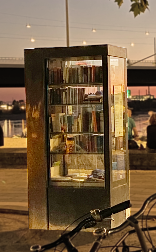 Glaskasten in Größe einer Telefonzelle mit ausgestellten Büchern zum Verleih am Rheinufer in Düsseldorf